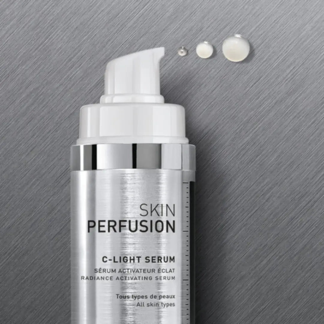 Fillmed Skin Perfusion C-Light Serum 30ml bottle on metallic background, with drops of serum, contains Vitamin C for skin radiance.