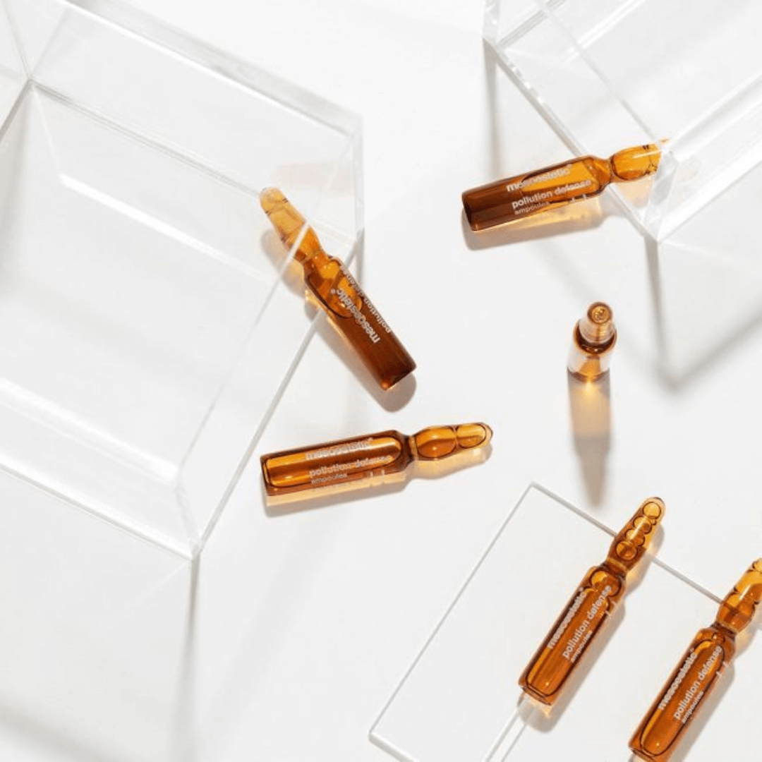 Multiple Mesoestetic Pollution Defense Ampoules scattered on a clear surface.