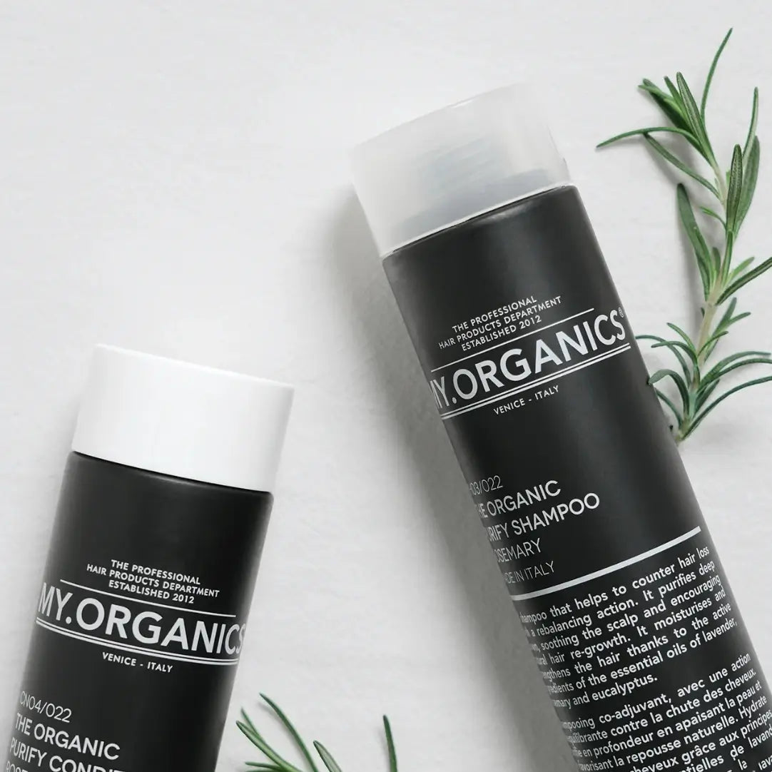 My Organics Purifying Shampoo and Purifying Conditioner bottles on a white surface, with rosemary sprigs in the background.