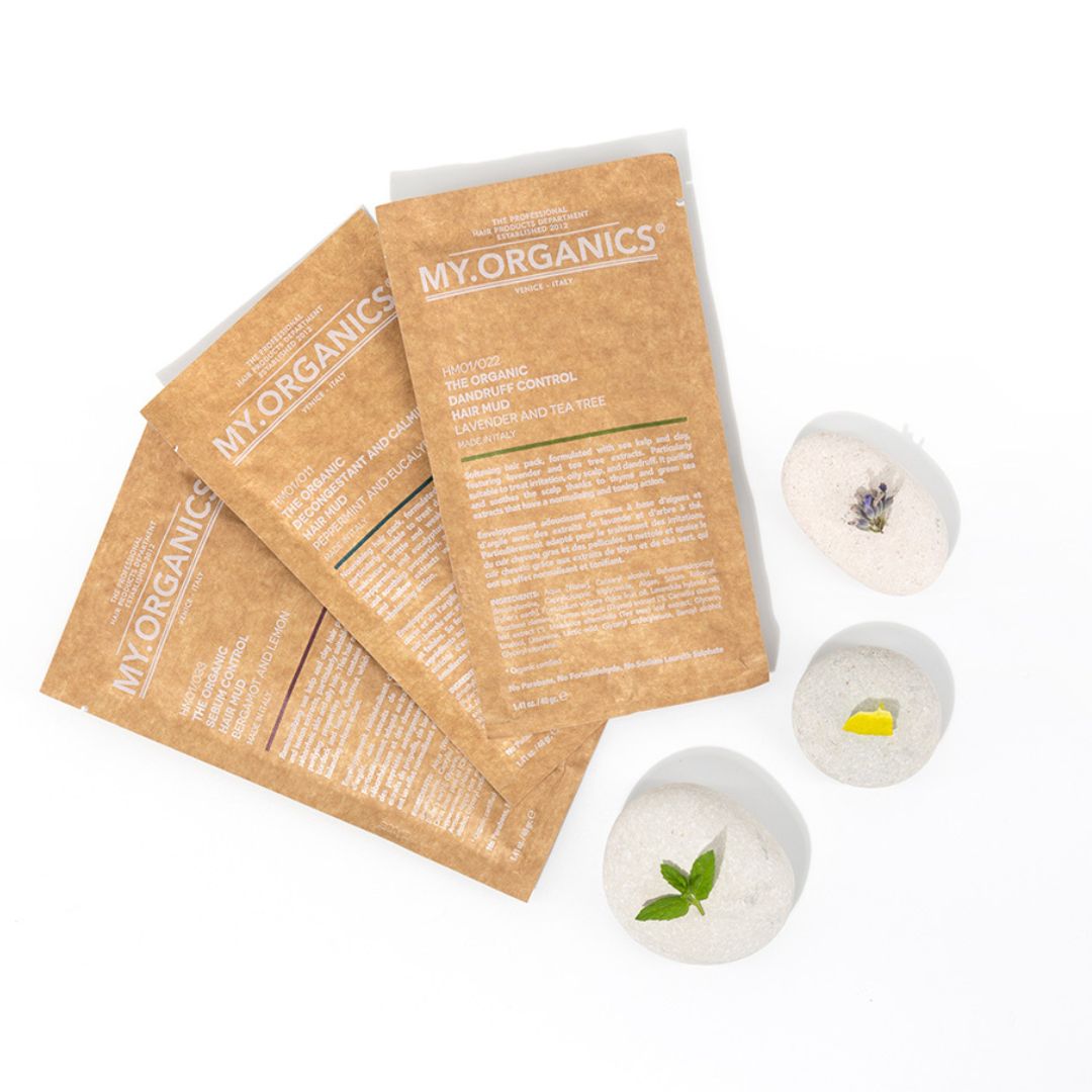 My Organics Hair Mud sachets arranged with decorative stones, effective for dandruff control and sebum regulation.